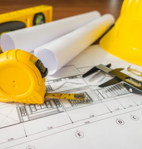 construction-plans-with-yellow-helmet-drawing-tools-bluep